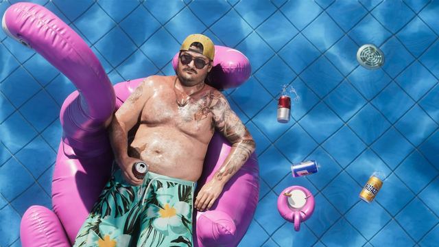 Cal laying on top of a flamingo floaty in a pool surrounded by floating cans.