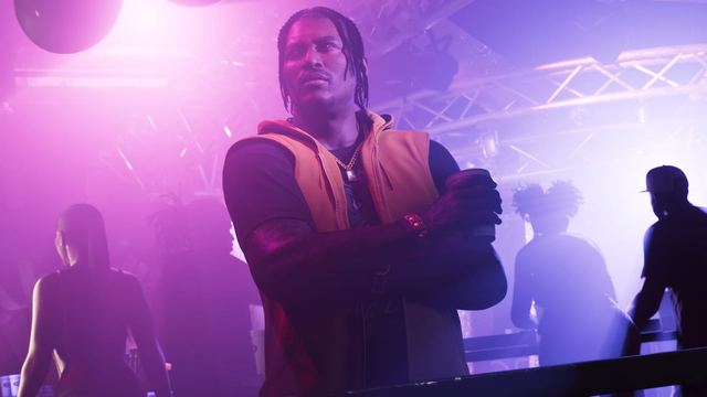 Dre'Quan in a club crossing his arms with a drink in his hand looking off to the side.