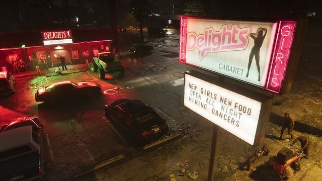 The outside parking lot of a club in Port Gellhorn at night with signs lit up advertising the cabaret. Several cars are parked, a few people linger outside of the club, and two people walk under the sign, one pushing a shopping cart.