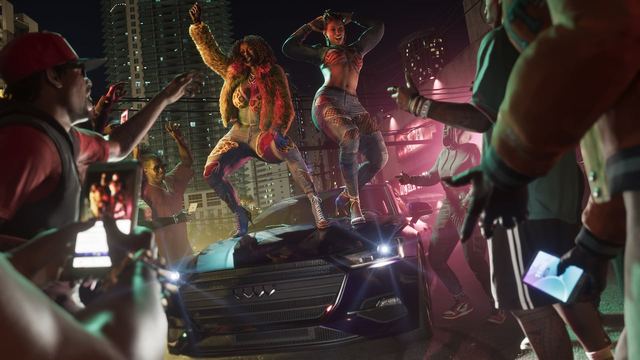 The Real Dimez dancing on top of the hood of a car with a group of people cheering them on with their phones held up.
