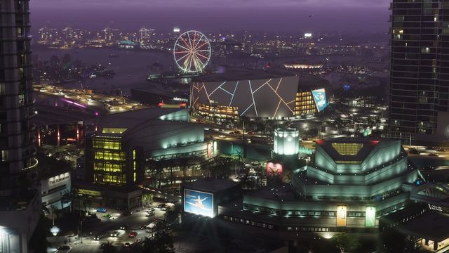 A Vice City skyline at night featuring a ferris wheel, cars driving, and tall buildings.